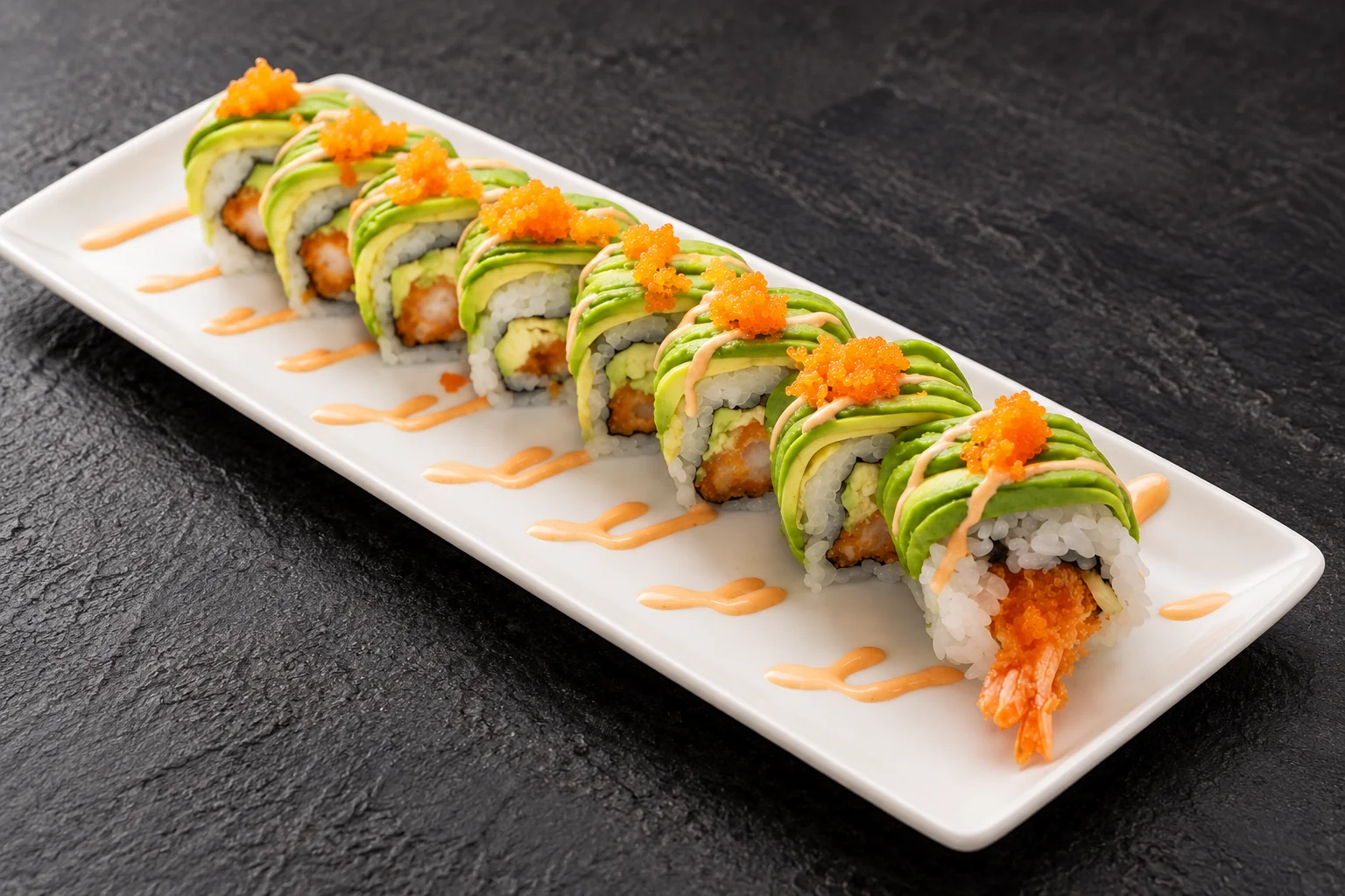 Roll avocat tempura crevette sur une assiette blanche rectangulaire, fond d'ardoise sombre.